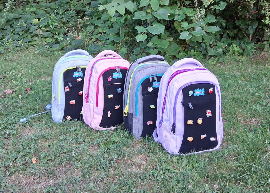 Four backpacks with colorful designs on a grassy background