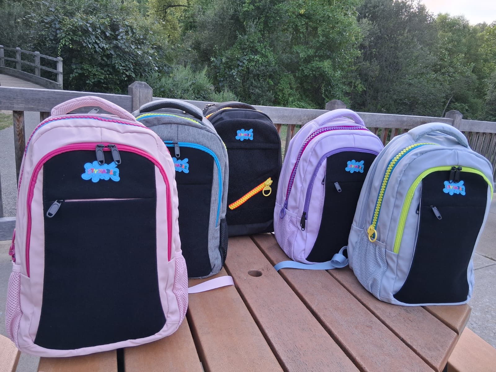 Set of colorful backpacks on a wooden surface with a natural background
